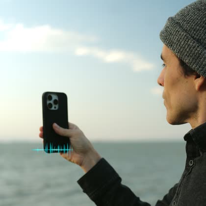A vlogger holding their phone with the rear camera facing them, a haptic pulse rippling from it.