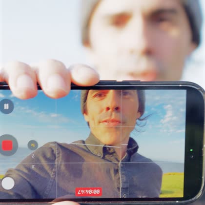 A phone screen showing the vlogger’s framed face alongside the recording controls and timer.